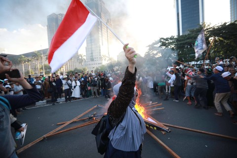 Massa pendukung paslon 01 dan 03 membakar spanduk bergambar Jokowi saat menggelar aksi unjuk rasa di sekitar Patung Kuda di sela mengawal keputusan Mahkamah Konstitusi pada Senin (22/4/2024) Foto: Aditia Noviansyah/kumparan