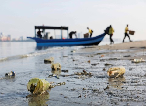 Gelas plastik dan barang-barang lainnya tergeletak di pantai saat para sukarelawan turun dari perahu selama kampanye pembersihan pantai yang diselenggarakan bersamaan dengan perayaan Hari Bumi di George Town, Malaysia (22/4/2024) Foto: Hasnoor Hussain/REUTERS