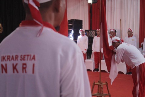 Narapidana tidak pidana terorisme mencium bendera Merah Putih saat mengikuti kegiatan ikrar setia NKRI  di Lapas Kelas IIA Gunung Sindur, Kabupaten Bogor, Rabu (24/4/2024). Foto: kumparan