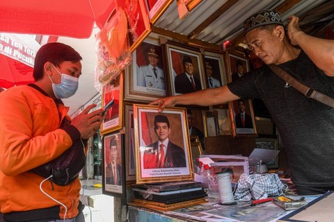 Pedagang menata foto pasangan Prabowo-Gibran sebagai Presiden dan Wakil Presiden 2024-2029 di kawasan Pasar Baru, Jakarta. Foto: Muhammad Adimaja/ANTARA FOTO