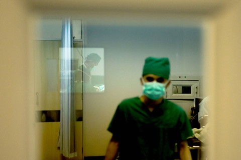 Refleksi Dokter: Refleksi pada kaca saat dokter sedang melakukan operasi di RSUD Tamansari Jakarta. Foto: Syawal Febrian Darisman/kumparan