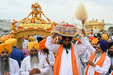 Seorang pendeta Sikh membawa Guru Granth Sahib (Kitab Suci Sikh) saat prosesi keagamaan menjelang ulang tahun Guru Sikh Teg Bahadur yang kesembilan di Kuil Emas di Amritsar (27/4/2024) Foto: Narinder Nanu/ AFP