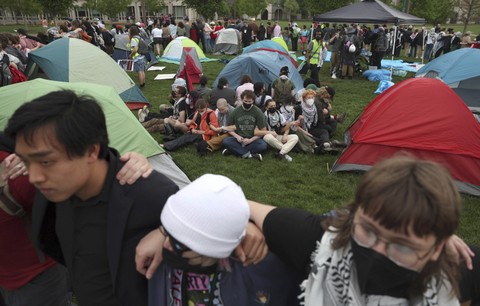 Pengunjuk rasa pro-Palestina bergandengan tangan di sekitar para peserta perkemahan saat polisi mendatangi perkemahan mereka di kampus Universitas Washington, Sabtu, 27 April 2024. Foto: Christine Tannous/St. Louis Pasca Pengiriman melalui AP