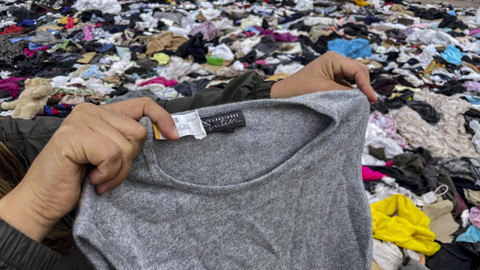 Seorang wanita mencari pakaian bekas di tengah berton-ton sampah di gurun Atacama, di Alto Hospicio, Iquique, Chile, pada 26 September 2021. Foto: MARTIN BERNETTI / AFP