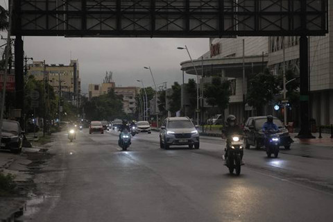 Pengemudi kendaraan di Kota Manado harus menyalakan lampu karena kondisi gelap dan juga pandangan terbatas akibat abu vulkanik. (foto: febry kodongan/manadobacirita)