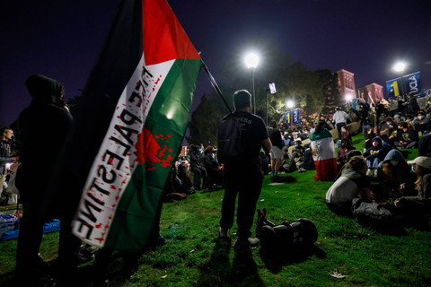 Pendukung pengunjuk rasa pro-Palestina duduk di tangga menuju perkemahan yang didirikan oleh mahasiswa dan aktivis pro-Palestina saat mereka berdemonstrasi di kampus Universitas California, Los Angeles (UCLA) di Los Angeles, California (1/5/2024) Foto: ETIENNE LAURENT / AFP