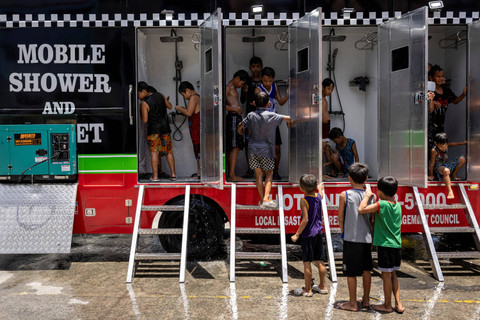 Anak-anak menggunakan mobile shower yang disediakan pemerintah setempat, di tengah panas ekstrem di Valenzuela, Metro Manila, Filipina. Foto: Eloisa Lopez/REUTERS