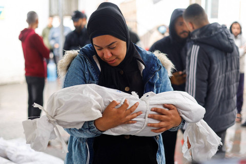 Seorang warga memegang jenazah anak Palestina yang tewas dalam serangan Israel, di tengah konflik yang sedang berlangsung antara Israel dan kelompok Islam Palestina Hamas di rumah sakit Abu Yousef al-Najjar di Rafah, di Jalur Gaza Selatan (6/5/2024). Foto: Mohammed Salem / REUTERS