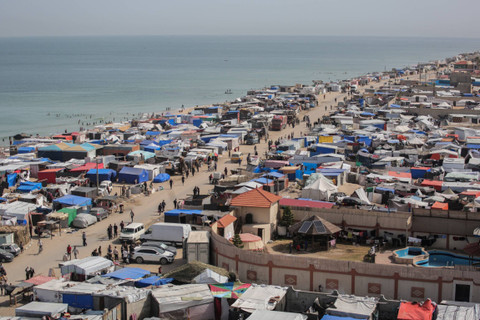 Warga Palestina berjalan di tengah tenda-tenda yang menampung para pengungsi, di sepanjang garis pantai di Deir el-Balah di Jalur Gaza tengah, Jumat (10/5/2024). Foto: AFP