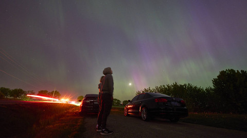 Banyak pengendara berhenti di sepanjang jalan pedesaan dekat London, Ontario untuk menyaksikan cahaya utara atau aurora borealis saat terjadi badai geomagnetik pada 10 Mei 2024. Foto: GEOFF ROBINS / AFP