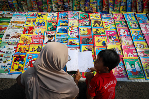 Orang tua dan anaknya memilih buku gambar saat Car Free Day (CFD) di kawasan Banjir Kanal Timur (BKT) Jakarta, Minggu (12/5/2024). Foto: Iqbal Firdaus/kumparan