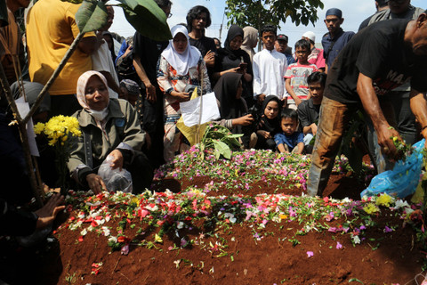 Sejumlah keluarga dan kerabat berdoa di depan makam korban kecelakaan bus rombongan SMK Lingga Kencana Depok, di TPU Parung Bingung, Depok, Jawa Barat, Minggu (12/5/2024). Foto: Yulius Satria Wijaya/ANTARA FOTO