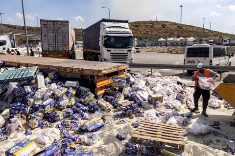 Seorang pekerja membersihkan tumpahan barang dari truk trailer yang membawa pasokan kemanusiaan ke Gaza yang dirusak warga dan aktivis sayap kanan Israel di sisi Israel dari penyeberangan Tarqumiyah dengan Tepi Barat yang diduduki, Senin (13/5/2024). Foto: Oren Ziv / AFP