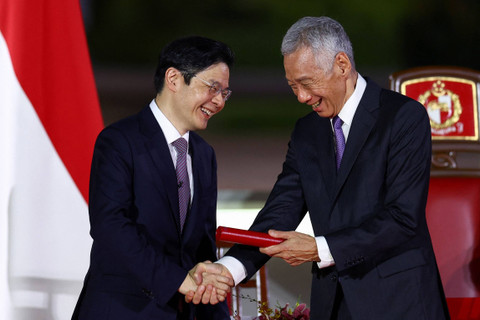 Perdana Menteri baru Singapura Lawrence Wong berjabat tangan dengan Menteri Senior Lee Hsien Loong saat ia dilantik sebagai Perdana Menteri keempat Singapura di Istana, di Singapura, Rabu (15/5/2024). Foto: Edgar Su/Reuters
