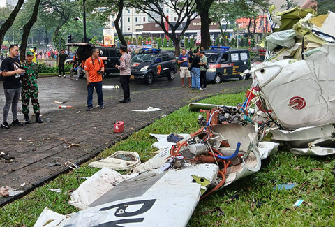 Sejumlah petugas berada di samping puing-puing pesawat yang jatuh di BSD Serpong, Tangerang Selatan, Banten, Minggu (18/5/2024). Foto: Rais Fauzan Azhar / ANTARA FOTO