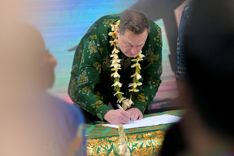 Elon Musk menandatangani dokumen sebelum meresmikan unit satelit Starlink di pusat kesehatan masyarakat di Denpasar, Bali, Indonesia (19/5/2024). Foto: Sonny Tumbelaka/AFP