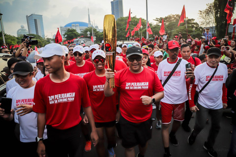 Sekjen PDIP Hasto Kristiyanto berlari sambil memegang obor bersama rombongan pembawa 'Obor Api Perjuangan' di Kemayoran, Jakarta, Kamis (23/5/2024). Foto: Jamal Ramadhan/kumparan
