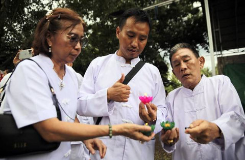 Umat Buddha saat pemasangan pelita teratai sebagai wujud dari penerangan hidup dan pengikisan kekotoran batin.