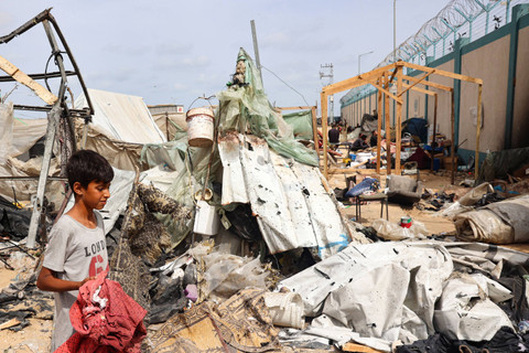 Seorang anak laki-laki Palestina mencari puing-puing di lokasi serangan Israel sehari sebelumnya di sebuah kamp pengungsi internal di Rafah di Jalur Gaza selatan (28/5/2024). Foto: EYAD BABA/AFP