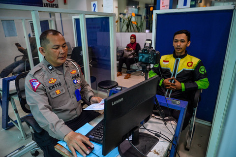 Petugas kepolisian mengambil foto warga yang mengajukan pembuatan surat izin mengemudi (SIM) di Polrestabes Bandung, Jawa Barat, Kamis (30/5/2024). Foto: ANTARA FOTO/Raisan Al Farisi