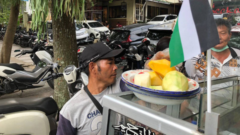 Surya (47), penjual rujak yang dagangannya laris akibat digelarnya aksi solidaritas untuk Palestina, di jalan Diponegoro, Bandung, Sabtu (8/6/2024). Foto: Robby Bouceu/kumparan