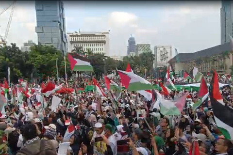 Massa aksi bela Palestina bentangkan bendera Palestina berukuran besar saat aksi bela Palestina di Kawasan Patung Kuda Arjuna Wiwaha, Jakarta Pusat, sore ini, Minggu (9/6/2024). Foto: Zamachsyari/kumparan