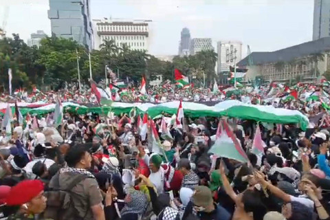Massa aksi bela Palestina bentangkan bendera Palestina berukuran besar saat aksi bela Palestina di Kawasan Patung Kuda Arjuna Wiwaha, Jakarta Pusat, sore ini, Minggu (9/6/2024). Foto: Zamachsyari/kumparan