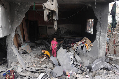 Sejumlah anak Palestina berada di antara puing-puing bangunan yang hancur usai serangan kamp pengungsi Nuseirat di Jalur Gaza tengah, Minggu (9/6/2024). Foto: Eyad BABA / AFP