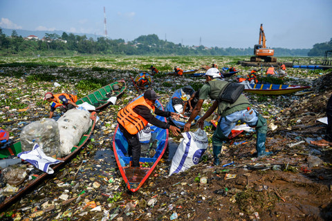 Petugas dengan menggunakan perahu kayu membersihkan sampah plastik yang mengendap di Sungai Citarum di Batujajar, Kabupaten Bandung Barat, Jawa Barat, Rabu (12/6/2024). Foto: Raisan Al Farisi/ANTARA FOTO