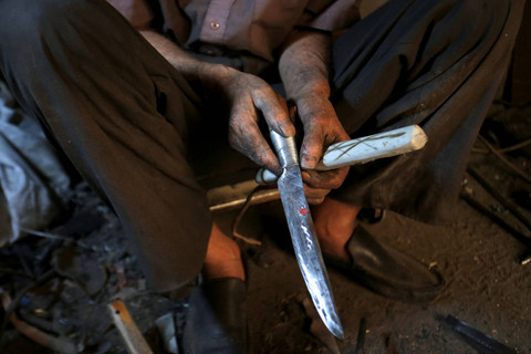 Pandai besi Abderrahmane Douffi memegang pisau tradisional 'Bou Saadi' yang diketahui digunakan untuk kurban Idul Adha di dalam bengkelnya di kota Bou Saada, Aljazair. Foto: Ramzi Boudina/REUTERS
