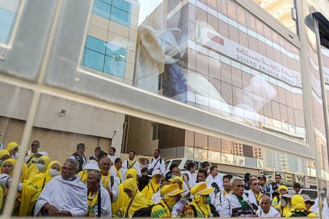 Refleksi jemaah calon haji Indonesia antre menaiki bus yang akan membawa mereka ke Arafah di Makkah, Arab Saudi, Jumat (14/6/2024). Foto: Sigid Kurniawan/Antara Foto