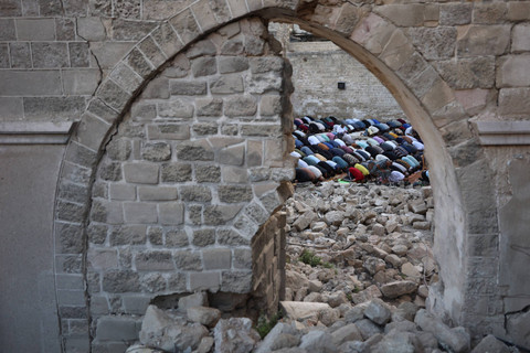 Warga Palestina melaksanakan salat Idul Adha di halaman Masjid Omari yang telah hancur akibat serangan udara israel di Kota Gaza, Minggu (16/6/2024). Foto: OMAR AL-QATTAA/AFP