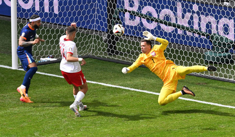 Memphis Depay dari Belanda beraksi bersama Jakub Kiwior dari Polandia dan Wojciech Szczesny pada Piala Eropa 2024 antara Polandia vs Belanda di Stadion Volkspark, Hamburg, Minggu (16/6/2024). Foto: Carmen Jaspersen/REUTERS