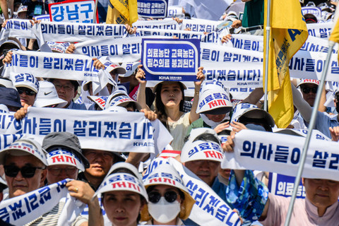 Seorang wanita (tengah) memegang plakat biru yang bertuliskan "Manipulasi (kebijakan) medis. Manipulasi (kebijakan) pendidikan" saat mogok kerja di Seoul, Korea Selatan (18/6/2024). Foto: Anthony Wallace/AFP