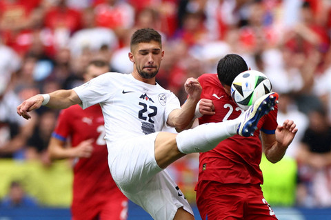 Pemain Slovenia Adam Gnezda Cerin beraksi dengan pemain Serbia Sasa Lukic pada pertandingan Slovenia melawan Serbia saat Piala Eropa 2024 di Allianz Arena, Jerman, Kamis (20/6/2024). Foto: Michaela Stache/REUTERS