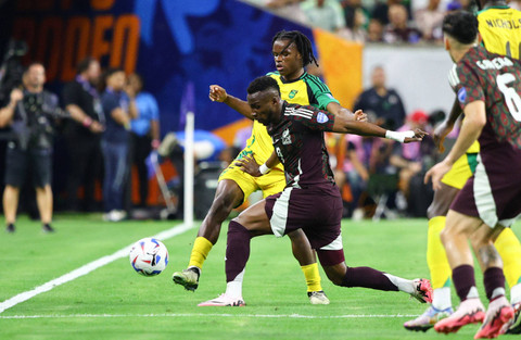 Penyerang Meksiko Julian Quinones berebut bola dengan pemain bertahan Jamaika Dexter Lembikisa selama pertandingan sepak bola grup B turnamen Copa America Conmebol 2024 antara Meksiko dan Jamaika di Stadion NRG di, Minggu (23/6/2024). Foto: Aric Becker/AFP