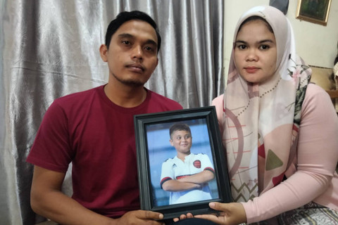 Afrinaldi dan Anggun Angriani, orang tua Afif Maulana, memegang foto anaknya. Foto: kumparan