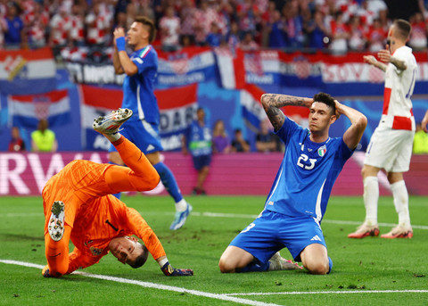 Dominik Livakovic dari Kroasia dan Alessandro Bastoni dari Italia bereaksi pada laga Kroasia melawan Italia saat Piala Eropa 2024 di Stadion Leipzig, Leipzig, Jerman, Senin (24/6/2024). Foto: Lisi Niesner/REUTERS 