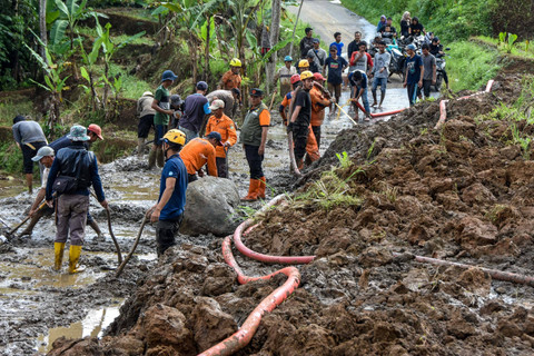 Sejumlah petugas BPBD Kabupaten Tasikmalaya dan relawan membersihkan material tanah longsor yang menimbun jalan penghubung antarkecamatan di Desa Nangtang, Kabupaten Tasikmalaya, Jawa Barat, Minggu (30/6/2024). Foto: Adeng Bustomi/ANTARA FOTO 
