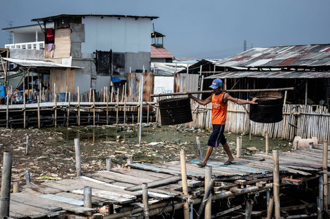 Warga mengangkut drum di kawasan permukiman semipermanen Muara Angke, Jakarta, Senin (1/7/2024). Foto: Aprilio Akbar/ANTARA FOTO