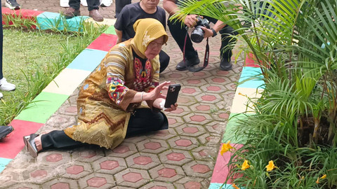 Momen Mensos Tri Rismaharini duduk selonjoran contohkan ambil objek foto bunga di sekitar lingkungan Balai Besar Pendidikan dan Pelatihan Kesejahteraan Sosial (BBPPKS) Bandung, Kecamatan Lembang, Kabupaten Bandung Barat, Jawa Barat, Senin (1/7/2024). Foto: Fadlan Nuril Fahmi/kumparan