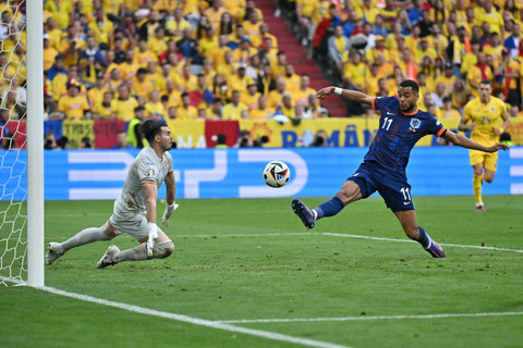 Pemain Timnas Belanda Cody Gakpo berebut bola dengan penjaga gawang Timnas Rumania Florin Nita pada pertandingan 16 besar Piala Eropa 2024 di Allianz Arena, Muenchen, Jerman, Selasa (2/7/2024). Foto: Miguel MEDINA / AFP