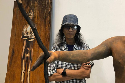 Asmudjo J Irianto berfoto dengan karyanya dalam Pameran Tubuh Antroposen yang digelar di Selasar Sunaryo Art Space, Jalan Bukit Pakar Timur, Ciburial, Kecamatan Cimenyan, Bandung, Jumat (5/7/2024). Foto: Robby Bouceu/kumparan