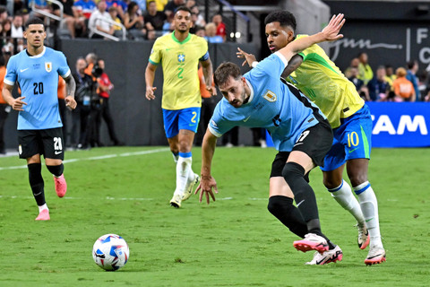 Pemain Timnas Brasil Rodrygo berebut bola dengan pemain Timnas Uruguay Matias Vina pada pertandingan perempat final Copa America 2024 di Stadion Allegiant, Las Vegas, Nevada, Amerika Serikat, Sabtu (6/7/2024). Foto: FREDERIC J. BROWN / AFP