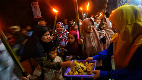 Warga sekitar yang menyediakan makanan ringan untuk peserta pawai obor 1 muharram yang melintas di depan rumah mereka, Minggu (7/7) Foto: ary priyanto/urban id