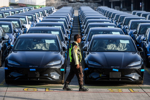 Petugas melintas di depan mobil di IPCC Terminal Kendaraan, Pelabuhan Tanjung Priok, Jakarta, Jumat (12/7/2024). Foto: ANTARA FOTO/Rivan Awal Lingga