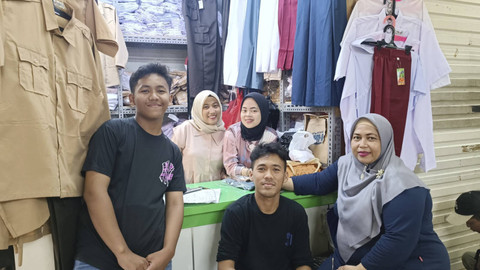 Rafiq (15) dan Kiki (23) kakak beradik penjual seragam sekolah bersama keluarganya di toko Harapan Jaya, Pasar Tanah Abang, Jakarta Pusat, Sabtu (13/7/2024). Foto: Fadlan Nuril Fahmi/kumparan