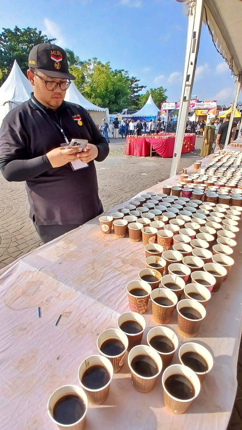 Salah satu panitia Museuk Rekor Indonesia (MURI) yang sedang menghitung ratusan gelas berisi kopi khas Sumsel yang dihidangkan di atas meja di Pelataran Benteng Kuto Besak Palembang, Sabtu (13/7) Foto: ary priyanto/urban id