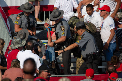 Seseorang dipindahkan oleh polisi dari tribun setelah senjata api ditembakkan ke arah kandidat Partai Republik Donald Trump dalam sebuah acara kampanye di Butler Farm Show Inc. di Butler, Pennsylvania,  Sabtu, (13/7/2024) waktu setempat. Foto: REBECCA DROKE/AFP