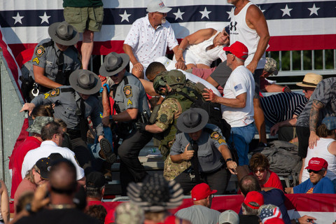 Seseorang dipindahkan oleh polisi dari tribun setelah senjata api ditembakkan ke arah kandidat Partai Republik Donald Trump dalam sebuah acara kampanye di Butler Farm Show Inc. di Butler, Pennsylvania,  Sabtu, (13/7/2024) waktu setempat. Foto: REBECCA DROKE/AFP